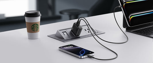 USB-C laptop charger charging multiple devices on a desk